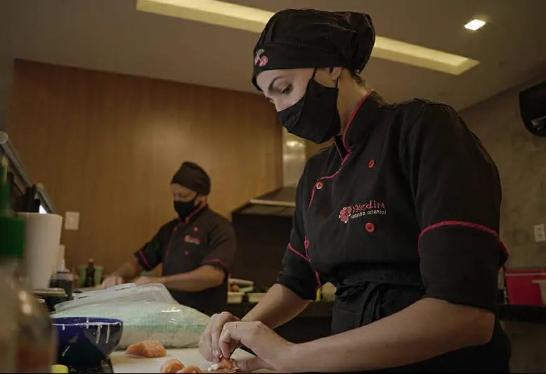 Equipe do Ykedin preparando os pratos na cozinha, de dólmã preto