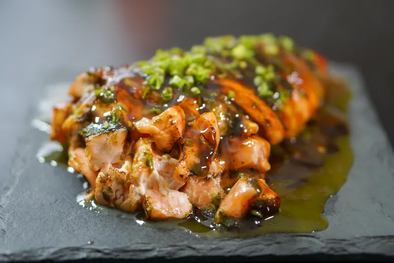 Temaki Flambado: salmão flambado com molho tarê e cebolinha sobre ardósia